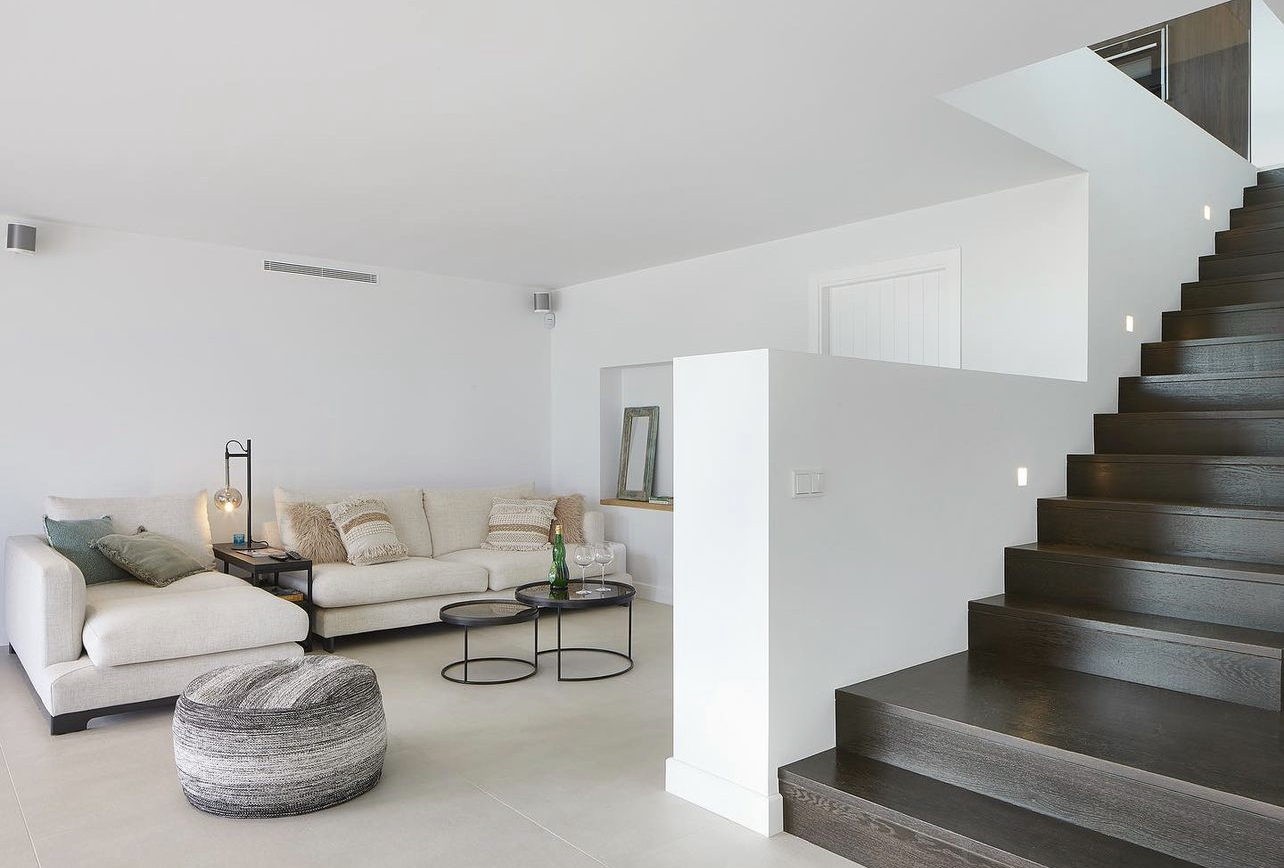 Interior lluminós amb escala negra i fusta en un habitatge rehabilitat