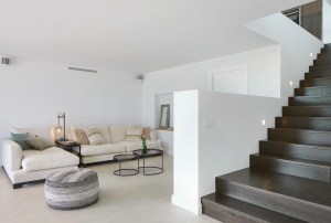 Interior lluminós amb escala negra i fusta en un habitatge rehabilitat